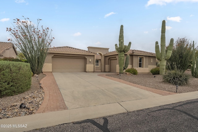 view of front of home with a tiled roof, stucco siding, driveway, and a garage