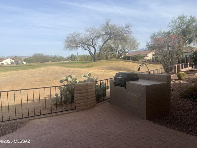 view of patio featuring a grill, an outdoor kitchen, and fence
