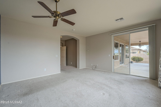 spare room featuring baseboards, light colored carpet, visible vents, arched walkways, and ceiling fan