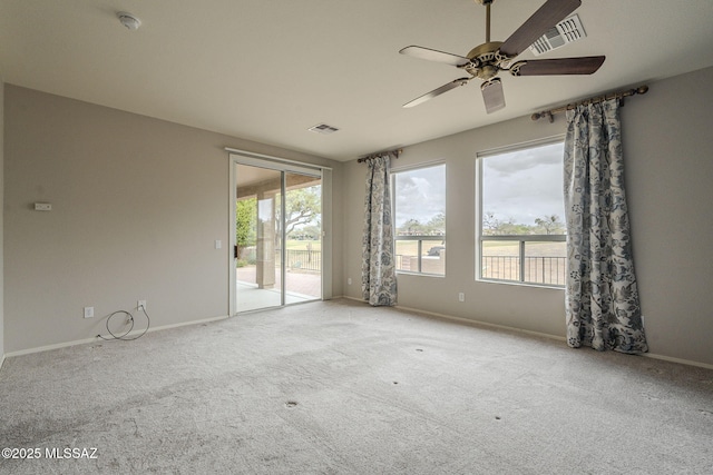 empty room featuring carpet flooring, a ceiling fan, a wealth of natural light, and visible vents