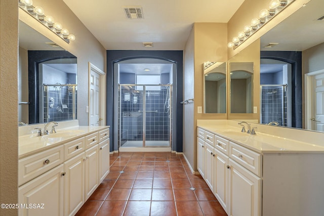bathroom with a stall shower, tile patterned floors, a sink, two vanities, and visible vents