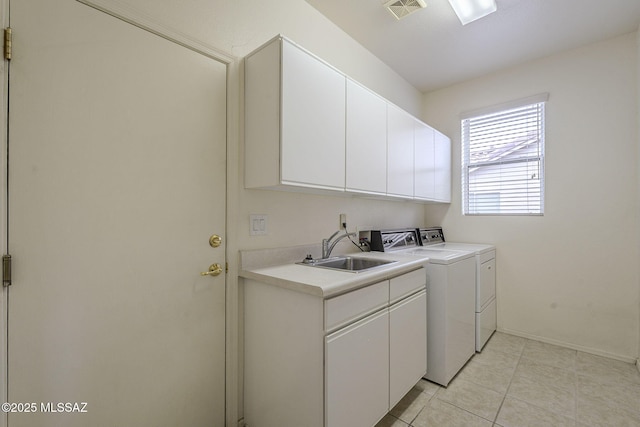 washroom with light tile patterned flooring, a sink, visible vents, washer and dryer, and cabinet space