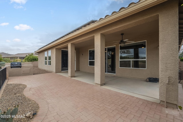view of patio / terrace featuring a ceiling fan, exterior kitchen, and fence