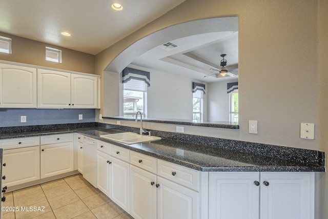 kitchen featuring a sink, a raised ceiling, dishwasher, arched walkways, and ceiling fan