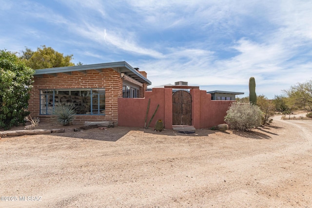 view of home's exterior featuring fence, a gate, and brick siding