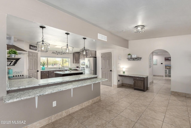 kitchen featuring stainless steel fridge with ice dispenser, a breakfast bar area, black electric cooktop, visible vents, and arched walkways
