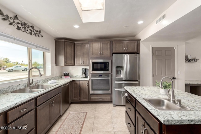 kitchen with dark brown cabinetry, visible vents, a sink, and appliances with stainless steel finishes