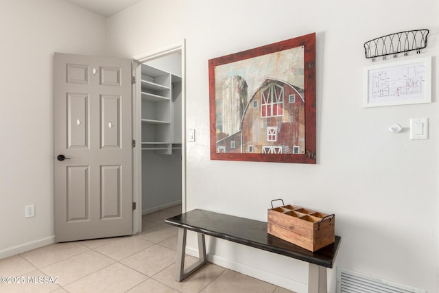 hallway with baseboards, visible vents, and light tile patterned floors