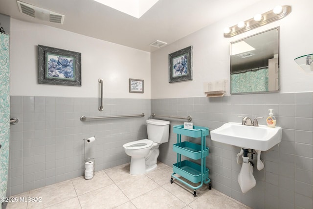 full bathroom with visible vents, toilet, tile patterned flooring, and wainscoting