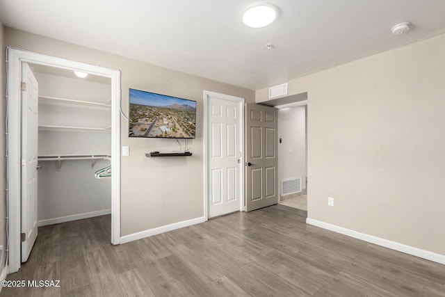 unfurnished bedroom featuring baseboards, visible vents, and wood finished floors