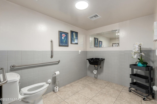 bathroom featuring tile walls, a wainscoted wall, visible vents, toilet, and tile patterned flooring