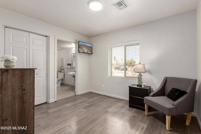 living area with baseboards, light wood-style floors, and visible vents