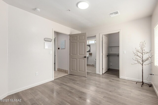 unfurnished bedroom with baseboards, multiple windows, light wood finished floors, and visible vents