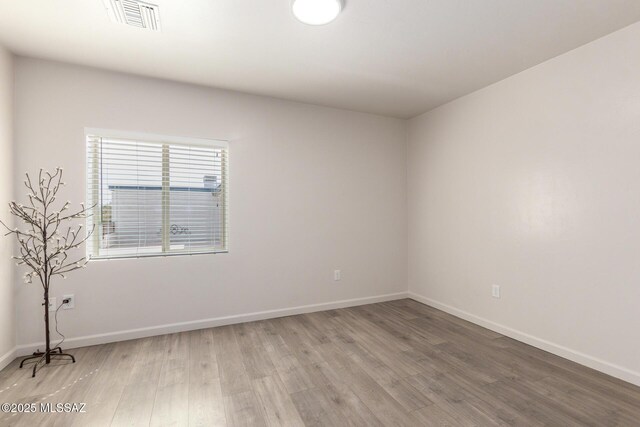 unfurnished room featuring baseboards, light wood finished floors, and visible vents