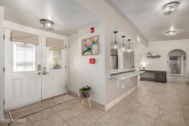 entryway with french doors, light tile patterned floors, baseboards, visible vents, and arched walkways