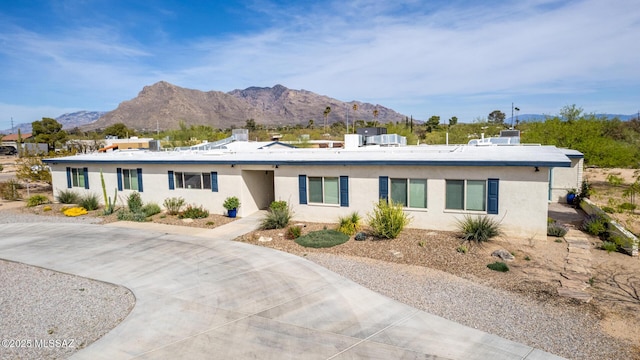 view of front facade featuring stucco siding, a mountain view, and concrete driveway