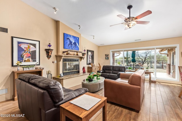 4720 E Wagon Train Rd, Tucson, AZ 85739 - living room featuring visible vents, wood finished floors, a ceiling fan, a glass covered fireplace, and vaulted ceiling