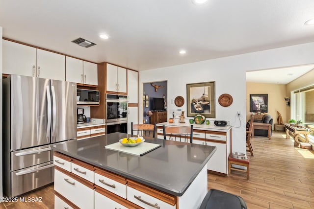 4720 E Wagon Train Rd, Tucson, AZ 85739 - kitchen featuring white cabinetry, visible vents, wood finished floors, and appliances with stainless steel finishes