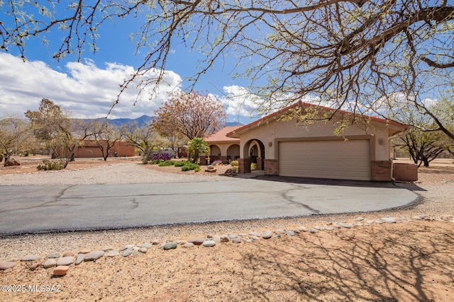 4720 E Wagon Train Rd, Tucson, AZ 85739 - view of front facade featuring a tile roof, stucco siding, an attached garage, brick siding, and aphalt driveway