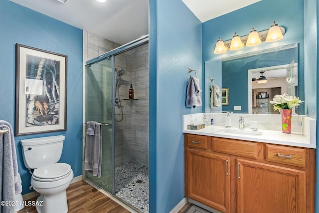 4720 E Wagon Train Rd, Tucson, AZ 85739 - bathroom featuring a stall shower, toilet, vanity, wood finish floors, and ceiling fan