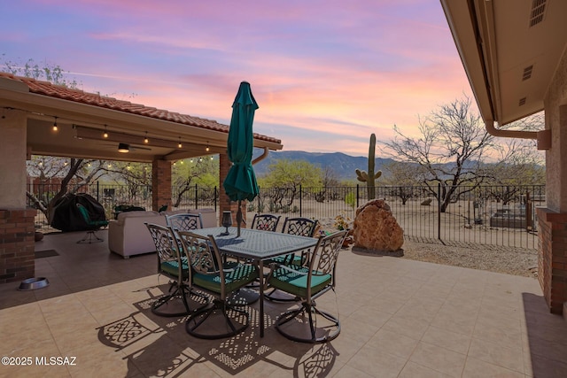 4720 E Wagon Train Rd, Tucson, AZ 85739 - patio terrace at dusk with area for grilling, outdoor dining area, a mountain view, and fence