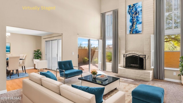 living room featuring a healthy amount of sunlight, a high ceiling, baseboards, and a fireplace