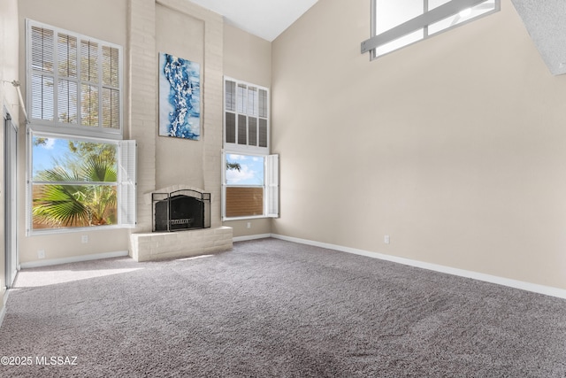 unfurnished living room featuring a fireplace, carpet flooring, a high ceiling, and baseboards