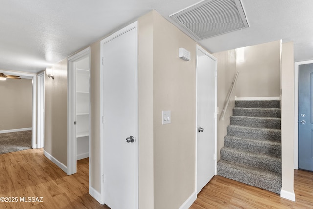 stairway featuring visible vents, baseboards, and wood finished floors