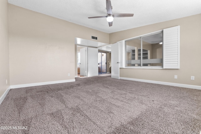 carpeted spare room with a textured ceiling, baseboards, a ceiling fan, and visible vents