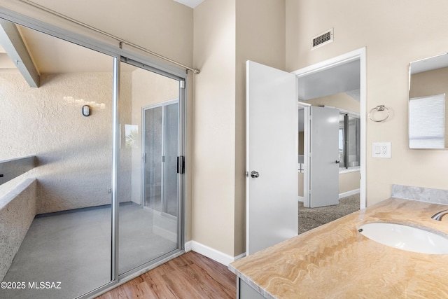 bathroom featuring wood finished floors, vanity, baseboards, and visible vents