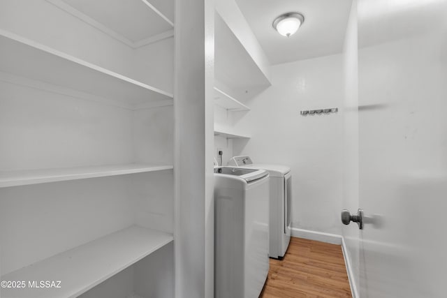 laundry area featuring washer and dryer, light wood finished floors, laundry area, and baseboards
