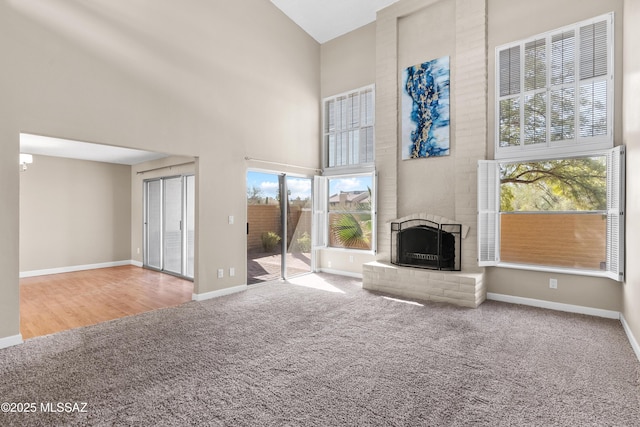 unfurnished living room featuring a fireplace, carpet, a high ceiling, and baseboards