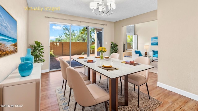 dining space with light wood-style flooring, a chandelier, and baseboards