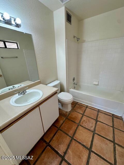 full bathroom featuring tile patterned floors, toilet, vanity,  shower combination, and a textured wall