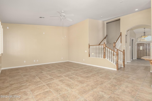 unfurnished room featuring visible vents, baseboards, stairs, a ceiling fan, and arched walkways