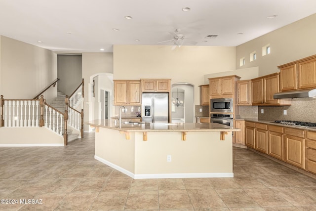 kitchen with ceiling fan, appliances with stainless steel finishes, arched walkways, under cabinet range hood, and a sink