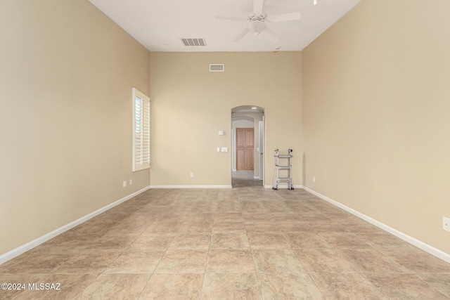 unfurnished room featuring arched walkways, baseboards, visible vents, and a ceiling fan