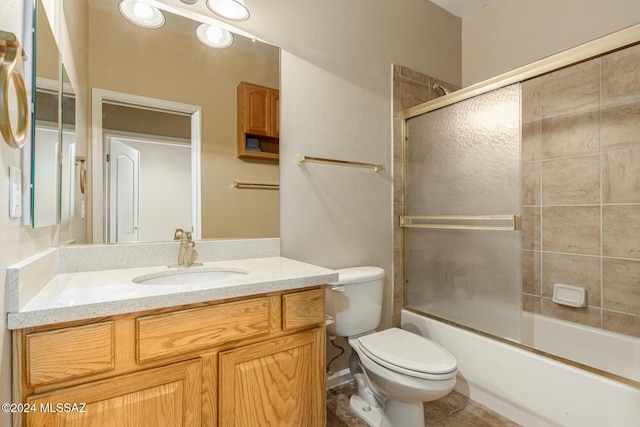 full bathroom with toilet, bath / shower combo with glass door, and vanity