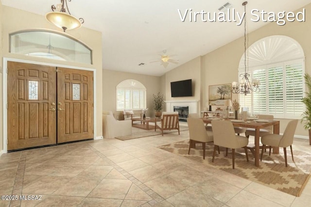 dining area with high vaulted ceiling, ceiling fan with notable chandelier, baseboards, visible vents, and a fireplace