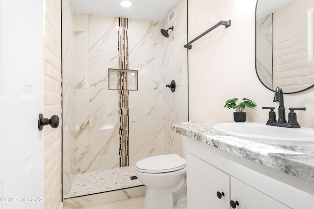 full bath featuring vanity, toilet, marble finish floor, visible vents, and tiled shower