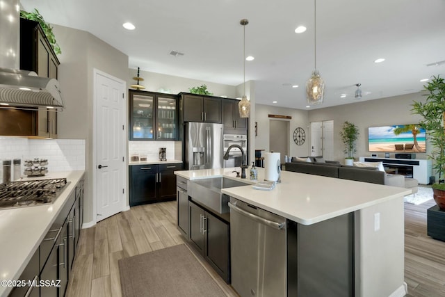 kitchen featuring light countertops, open floor plan, appliances with stainless steel finishes, and a sink