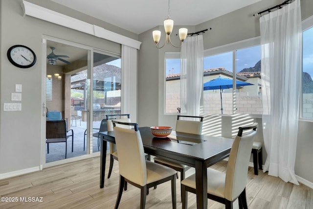dining room with baseboards, light wood finished floors, and ceiling fan with notable chandelier
