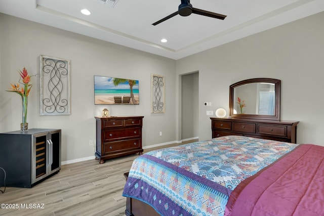 bedroom with light wood-style floors, recessed lighting, baseboards, and a raised ceiling