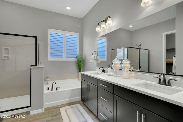 full bath featuring wood finished floors, a sink, a garden tub, and a stall shower