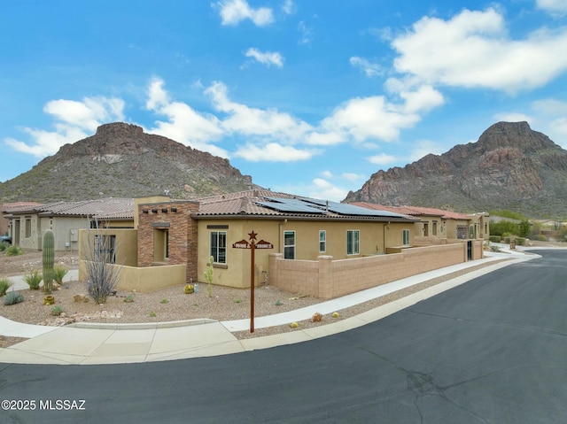 view of home's exterior with a mountain view, stucco siding, fence private yard, and solar panels