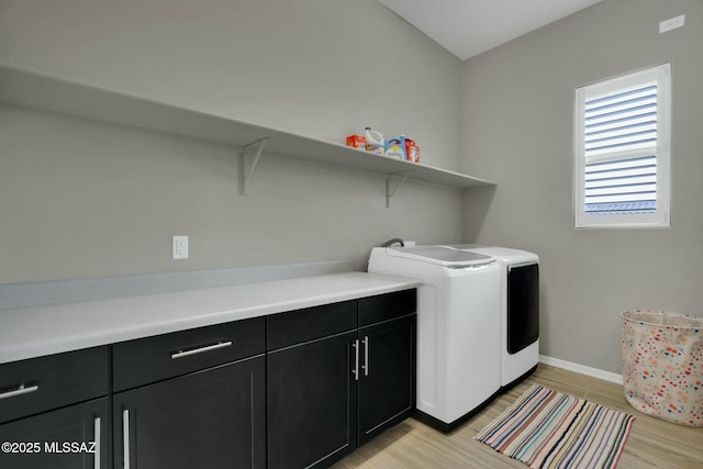 clothes washing area with light wood-type flooring, cabinet space, baseboards, and washer and dryer