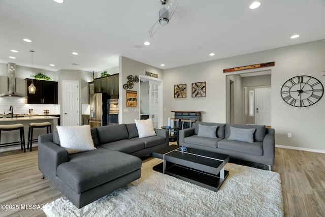 living area featuring light wood-type flooring, recessed lighting, and baseboards