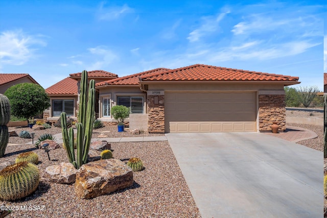 mediterranean / spanish house featuring concrete driveway, stone siding, an attached garage, and a tile roof