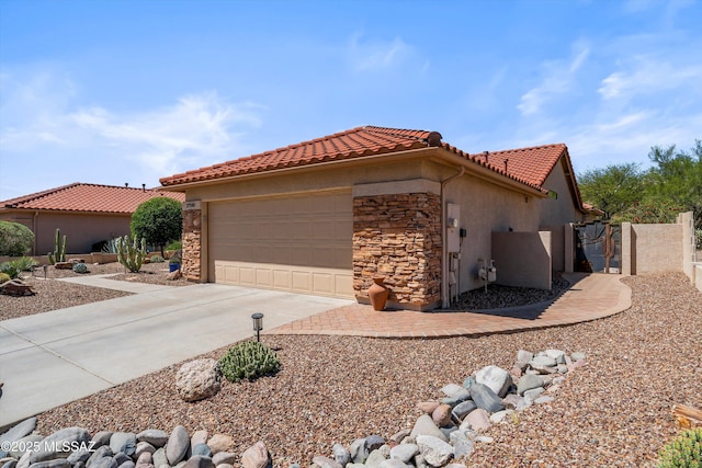 view of home's exterior with concrete driveway, a garage, stone siding, and a tile roof