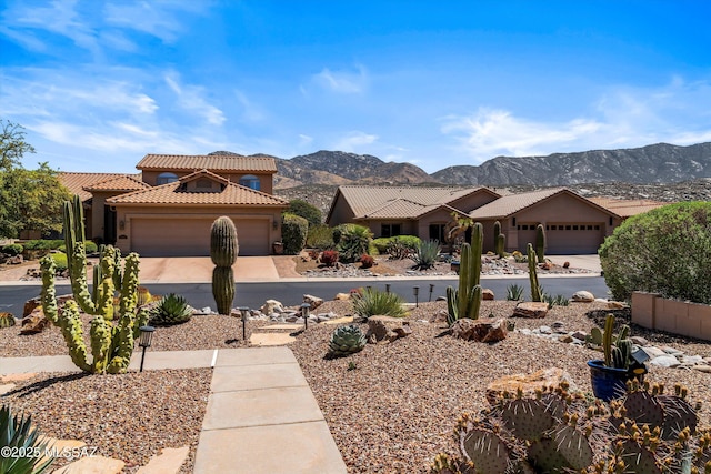 view of front of property with a tiled roof, a mountain view, a garage, and concrete driveway